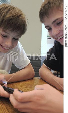 High school students teens gen z two gue, friends playing online video game e-sport play diverse gadgets. Guys playing on the phone. 127292572