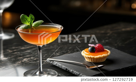 Elegant snacktail composition with vermouth cocktail and mini tart served in rich lighting on marble. 127292719
