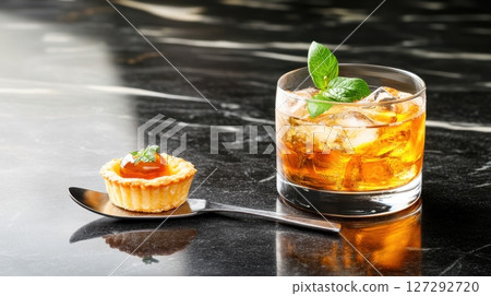Elegant snacktail composition with vermouth cocktail and mini tart served in rich lighting on marble. 127292720