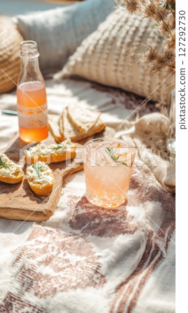 Natural daylight picnic setup with spritz cocktail and artisan crostini, laid-back mood, rustic textiles, outdoor brunch vibe, eco-friendly styling 127292730