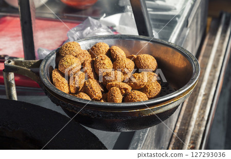 Freshly fried falafel balls being prepared on a street cart in the sun 127293036