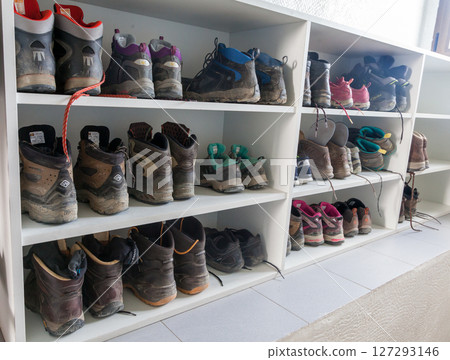 A variety of hiking boots lined up neatly on shelves in a cozy cabin after an outdoor adventure 127293146