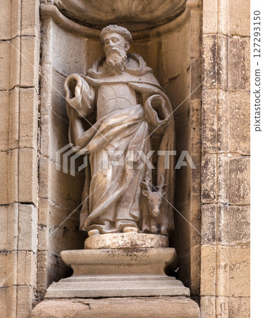 Stone statue of a figure holding a staff in Obanos, Spain, on a sunny afternoon 127293150