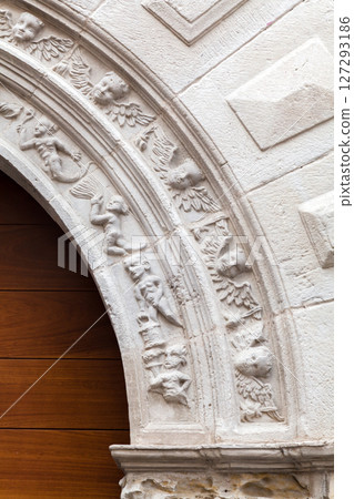 Intricate stone carvings on an archway embellish a historic building in a quaint town 127293186
