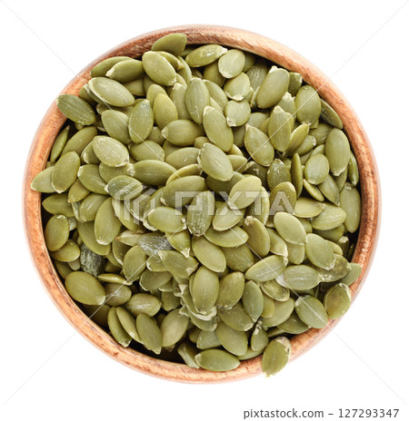 Top view of wooden bowl with peeled pumpkin seeds on white background. Top view of wooden bowl with peeled pumpkin seeds on white background. 127293347