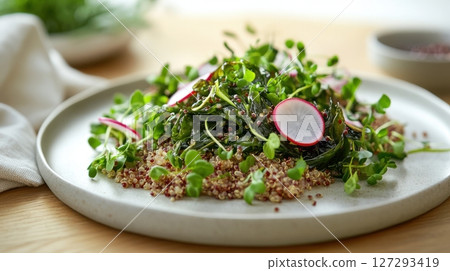High-quality image of a warm quinoa and wakame salad drizzled with silky truffle sauce, plated on a minimalist white plate with elegant garnish, perfect for gourmet food photography. 127293419