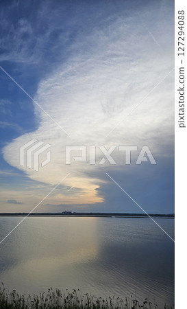 Landscape with unusually shaped white cloud in the evening sky over the lake 127294088