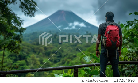 Man with pink backpack enjoying the view of Volcano in exotic jungle during late afternoon sunlight 127294686