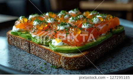 Artisanal toast topped with smoked salmon, avocado, cream cheese, and dill on marble countertop in minimalist Scandinavian style 127295185