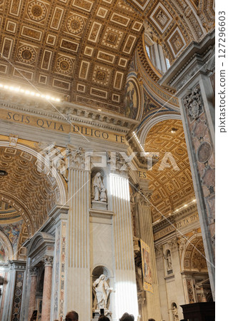 Decorative golden coffered ceiling and detailed pillars with frescoes and carvings inside Saint Peters Basilica showcasing baroque Catholic architecture in Vatican City. High quality photo 127296603