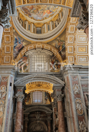 Ornate vaulted ceilings and central dome of Saint Peters Basilica in Vatican City richly decorated with golden details frescoes and religious architecture. High quality photo 127296620