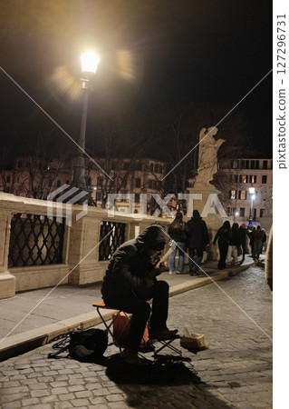 Street musicians performing on cobblestone Roman bridge at night under lamplight in romantic historical city ambiance Rome Italy. High quality photo Street musicians performing on cobblestone Roman bridge at night under lamplight in romantic historical city ambiance Rome Italy. High quality photo 127296731