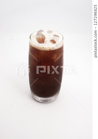 iced coffee or cold brew in tall clear glass with ice cubes and creamy foam served on white background. High quality photo iced coffee or cold brew in tall clear glass with ice cubes and creamy foam served on white background. High quality photo 127296825