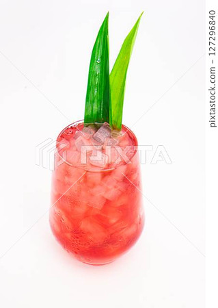 red berry cocktail served in clear glass with crushed ice and green tropical leaves isolated on white background. High quality photo 127296840