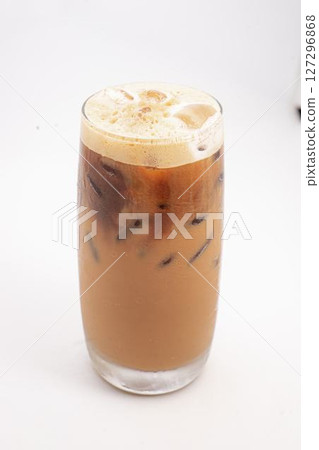 iced coffee with cream and ice cubes served in tall clear glass with foamy top photographed on white background. High quality photo 127296868