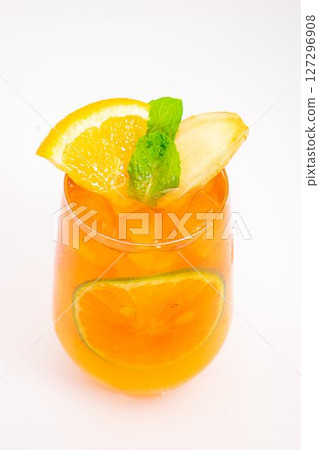 refreshing orange citrus cocktail with sliced lemon and mint leaves served in clear glass over ice on white background. High quality photo 127296908