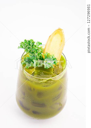 green vegetable juice with ice served in glass and garnished with fresh kale and ginger slice on white background. High quality photo green vegetable juice with ice served in glass and garnished with fresh kale and ginger slice on white background. High quality photo 127296981