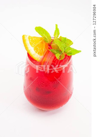 vibrant red berry cocktail with orange slice and fresh mint leaves served in clear glass with ice on white background. High quality photo 127296984