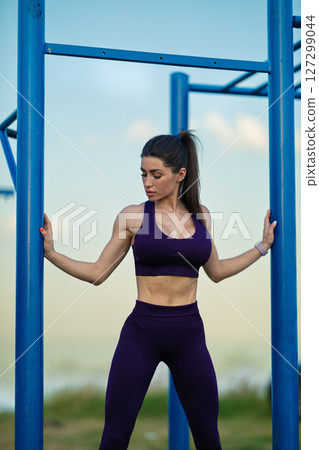 Sporty girl confidently poses in athletic wear on a sports ground near the sea, emphasizing her strength and fitness The setting and time create an inspiring atmosphere for outdoor exercise Sporty girl confidently poses in athletic wear on a sports ground near the sea, emphasizing her strength and fitness The setting and time create an inspiring atmosphere for outdoor exercise 127299044