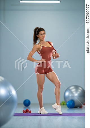 sporty girl is posing in a well lit gym, demonstrating strength and confidence 127299077