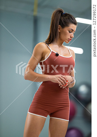 sporty girl announcer stands confidently in a contemporary fitness studio She is dressed in a fitted outfit, preparing to engage with an audience 127299172