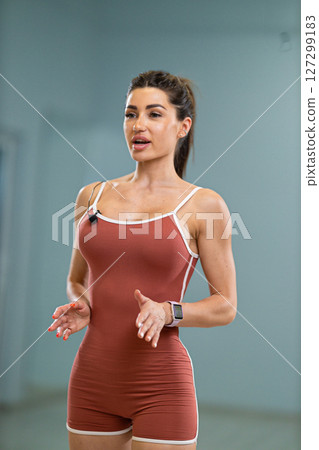 Sporty girl announcer engages the audience while presenting at a fitness event inside a modern gym Her confident demeanor inspires the attendees Sporty girl announcer engages the audience while presenting at a fitness event inside a modern gym Her confident demeanor inspires the attendees 127299183