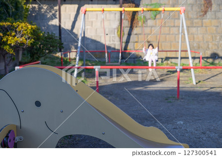 一個小女孩獨自在公園的鞦韆上玩耍 一個小女孩獨自在公園的鞦韆上玩耍 127300541