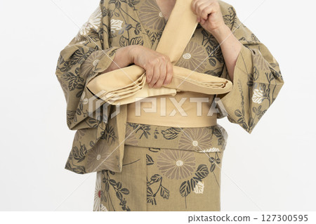 自己穿上浴衣。自己穿上浴衣。把腰帶繫在身前。 127300595
