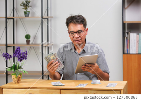 Senior man managing money for bills paying and investment. 127300863