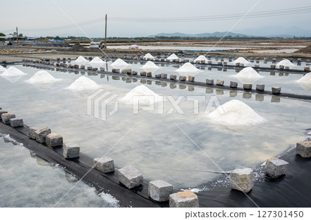 Salt mounds form in evaporation pools near Asian village using natural sun drying in rural area 127301450