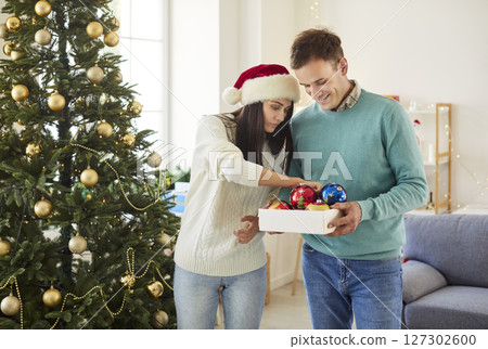 Husband And Wife Selecting Ornaments To Decorate The Christmas Tree At Home 127302600