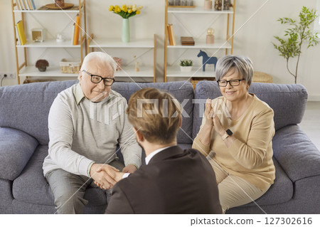 Senior couple shaking hands with financial advisor reaching agreement in health insurance. 127302616