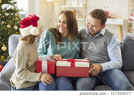 Parents And Child Opening Gifts At Home On Christmas Or New Year 127302677