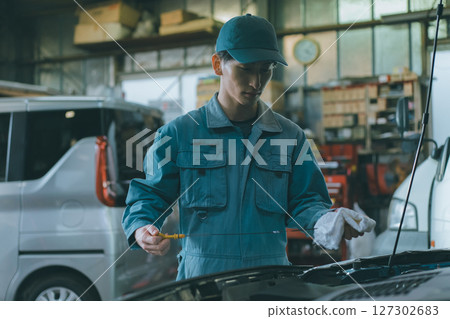 Auto mechanic checking engine oil Auto mechanic checking engine oil 127302683