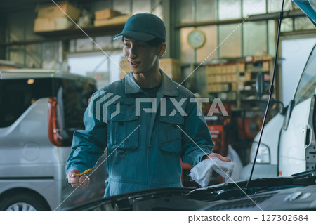 Auto mechanic checking engine oil Auto mechanic checking engine oil 127302684