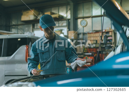 Auto mechanic checking engine oil 127302685