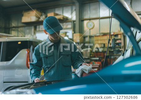 Auto mechanic checking engine oil Auto mechanic checking engine oil 127302686