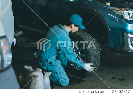 Automobile mechanic exchanging tires 127302747