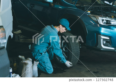 Automobile mechanic exchanging tires 127302748