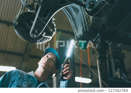 Automobile mechanic inspecting suspension 127302769