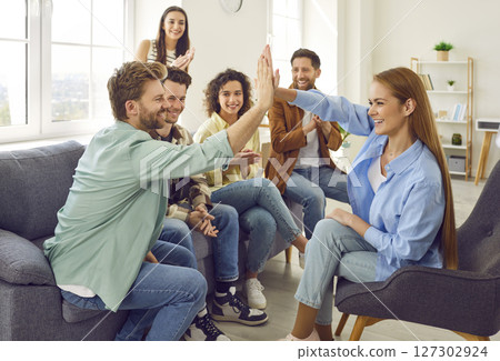 Group of happy friends giving high five sitting on sofa at home. Teamwork concept. 127302924