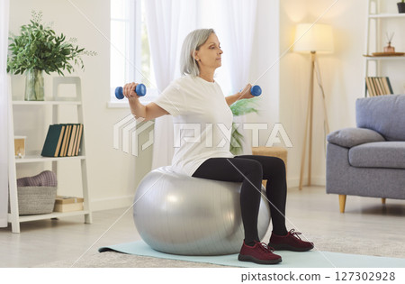 Old Woman Doing Fitness Training With Dumbbells And Fitball At Home 127302928