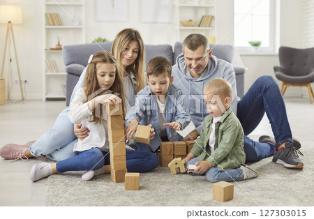 Parents playing an educational game with children in the living room at home together. 127303015
