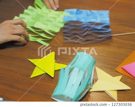 Child's hands making origami Tanabata decorations 127303036