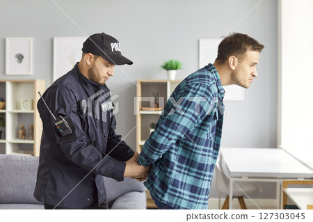 Police officer, legal authority policeman making processing arrest of guilty man, handcuffing  127303045