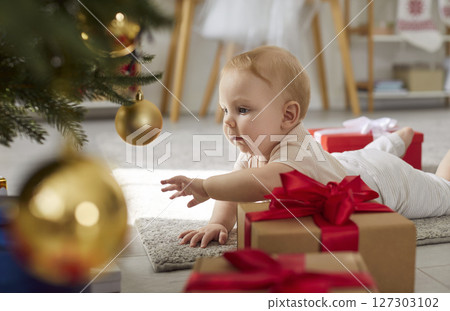 Baby Crawling Near Christmas Tree With Gifts At Home 127303102