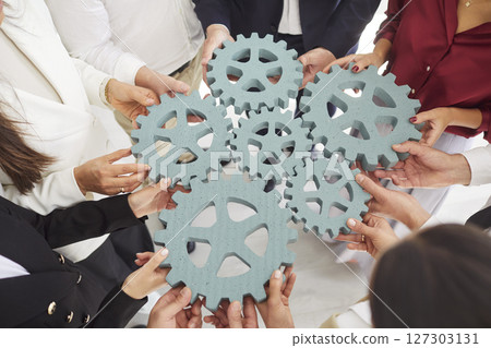 Close-Up Of Hands Holding Gears Symbolizing Teamwork Close-Up Of Hands Holding Gears Symbolizing Teamwork 127303131