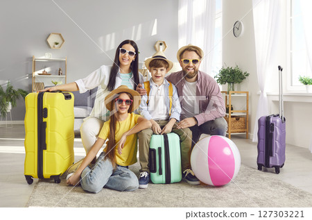 Happy family with kids sitting on the floor with packed suitcases ready to fly to tropical resort. Happy family with kids sitting on the floor with packed suitcases ready to fly to tropical resort. 127303221
