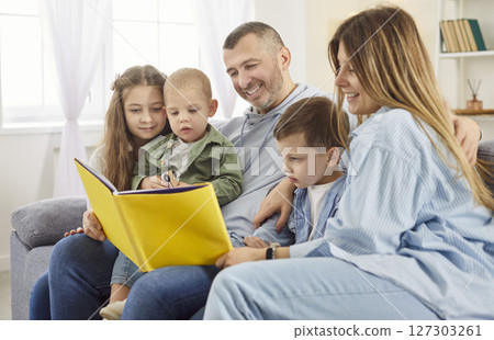 Children and parents reading book together at home for bonding, entertainment and quality time. Children and parents reading book together at home for bonding, entertainment and quality time. 127303261