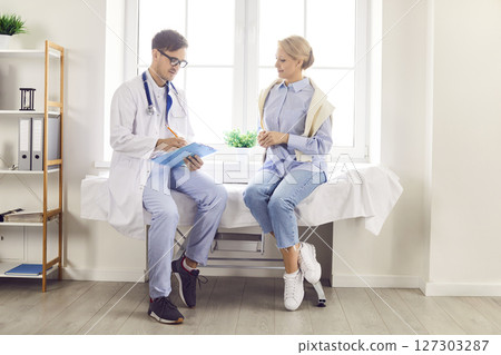 Young woman patient visiting male physician at doctor office during medical examination. 127303287